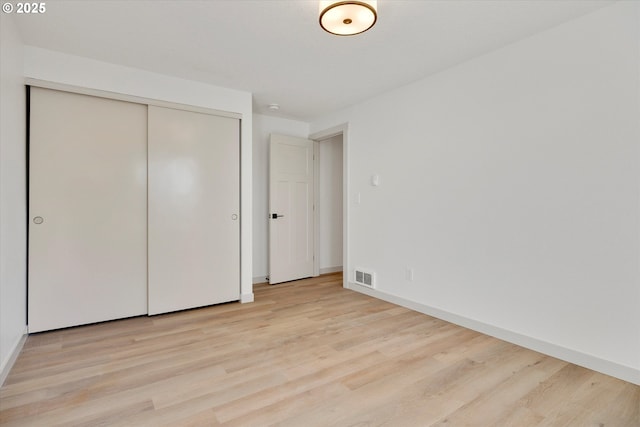 unfurnished bedroom with light hardwood / wood-style flooring and a closet