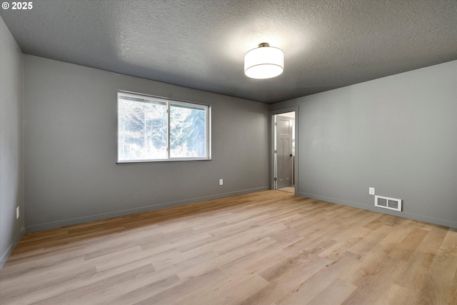 spare room featuring a textured ceiling and light wood-type flooring