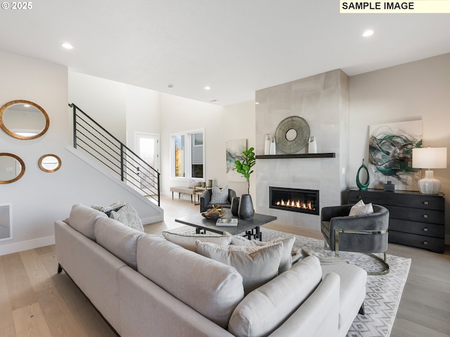 living area with light wood-type flooring, visible vents, recessed lighting, stairs, and a tile fireplace