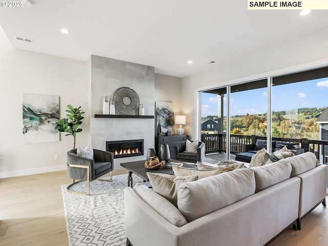 living room with visible vents, baseboards, recessed lighting, light wood-style flooring, and a fireplace