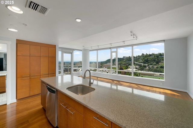 kitchen with sink, light wood-type flooring, stainless steel dishwasher, and light stone countertops