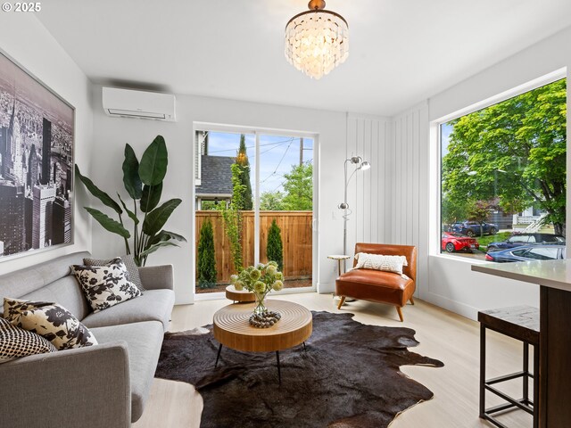 sitting room with a wall unit AC, wood finished floors, and a chandelier