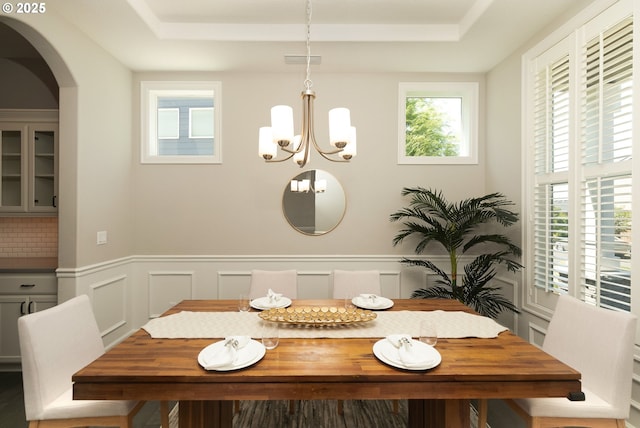 16922 NW Madrone St, Portland, OR 97229 - dining room with a chandelier, a wainscoted wall, arched walkways, a raised ceiling, and a decorative wall