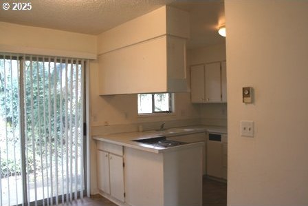 14737 SW Hall Blvd, Tigard, OR 97224 - kitchen featuring white cabinetry, a peninsula, light countertops, a textured ceiling, and a sink