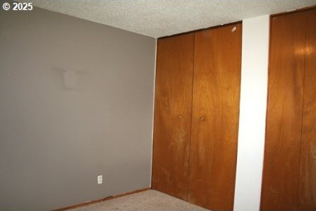 14737 SW Hall Blvd, Tigard, OR 97224 - unfurnished bedroom featuring a closet, a textured ceiling, and carpet