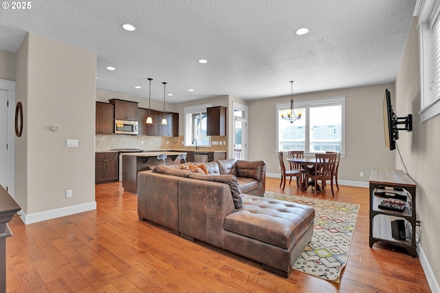 14670 SW 78th Ave, Tigard, OR 97224 - living room with a chandelier, light wood-style floors, baseboards, a textured ceiling, and recessed lighting