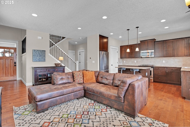 14670 SW 78th Ave, Tigard, OR 97224 - living area with light wood-type flooring, a textured ceiling, stairs, recessed lighting, and baseboards