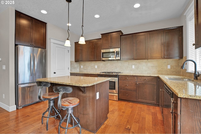 14670 SW 78th Ave, Tigard, OR 97224 - kitchen featuring appliances with stainless steel finishes, a sink, light wood finished floors, light stone counters, and recessed lighting