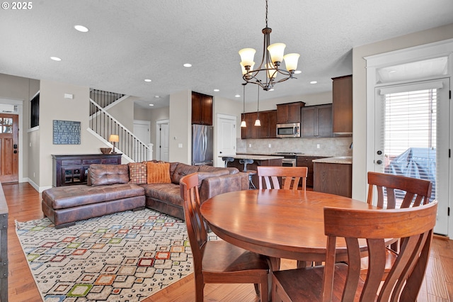 14670 SW 78th Ave, Tigard, OR 97224 - dining space featuring a chandelier, light wood-type flooring, recessed lighting, stairs, and a textured ceiling