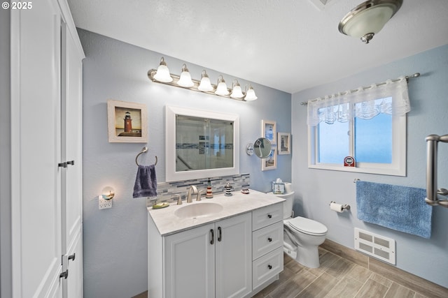 bathroom featuring vanity, tasteful backsplash, and toilet