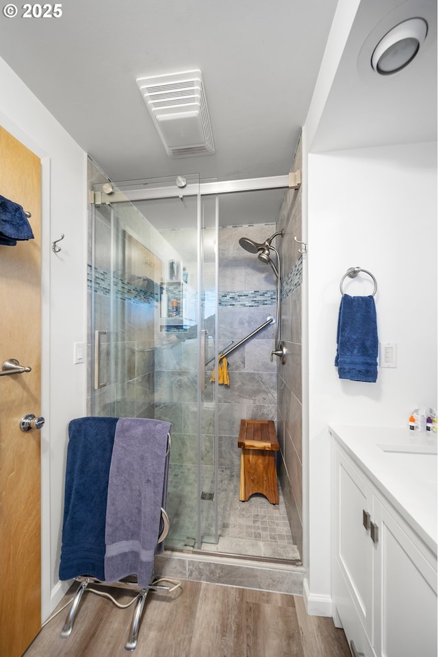 bathroom featuring vanity, a shower with shower door, and wood-type flooring