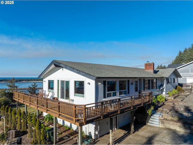 rear view of property featuring a deck with water view and a garage