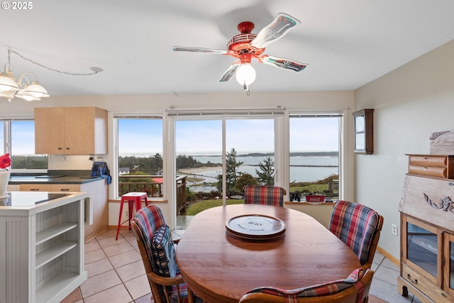 tiled dining space with a water view and ceiling fan with notable chandelier