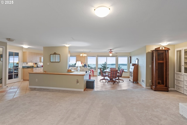 kitchen featuring light carpet, light brown cabinetry, and an island with sink