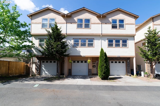 multi unit property with a garage, fence, and driveway