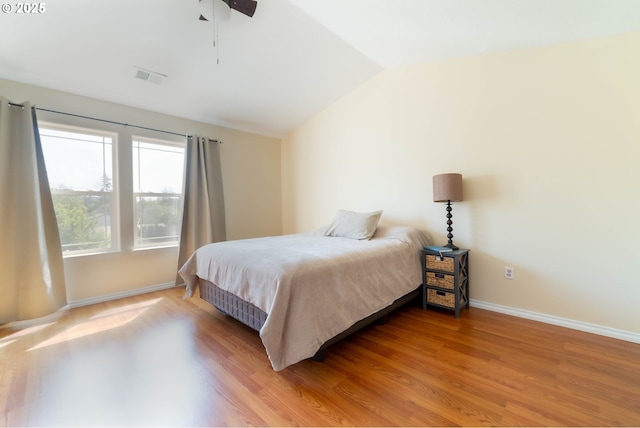 bedroom with lofted ceiling, light wood-type flooring, and baseboards