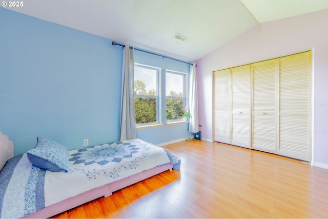 bedroom featuring lofted ceiling, wood finished floors, baseboards, and a closet
