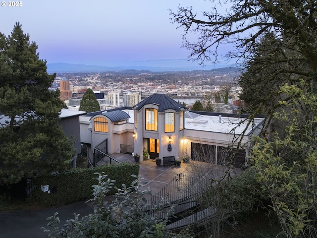 view of front facade featuring a view of city, a standing seam roof, metal roof, and stucco siding