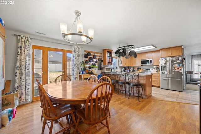 dining area featuring french doors, a chandelier, and light hardwood / wood-style flooring