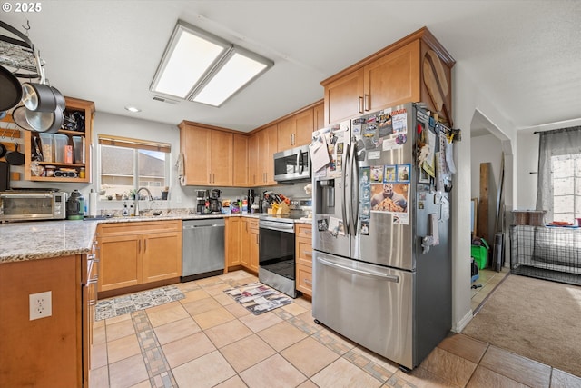 kitchen featuring light stone counters, light colored carpet, plenty of natural light, and stainless steel appliances