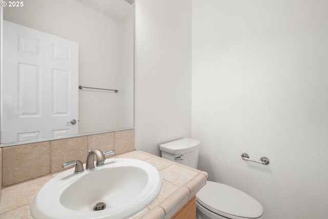 bathroom with toilet, backsplash, and vanity