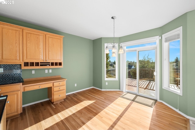 interior space with a notable chandelier, built in desk, and wood-type flooring