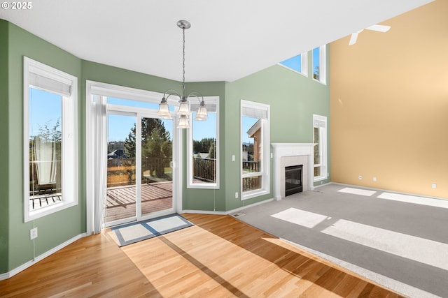 unfurnished living room with a notable chandelier, a healthy amount of sunlight, and hardwood / wood-style floors