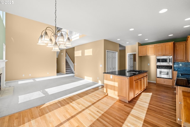 kitchen featuring stainless steel appliances, an inviting chandelier, light hardwood / wood-style flooring, hanging light fixtures, and a kitchen island