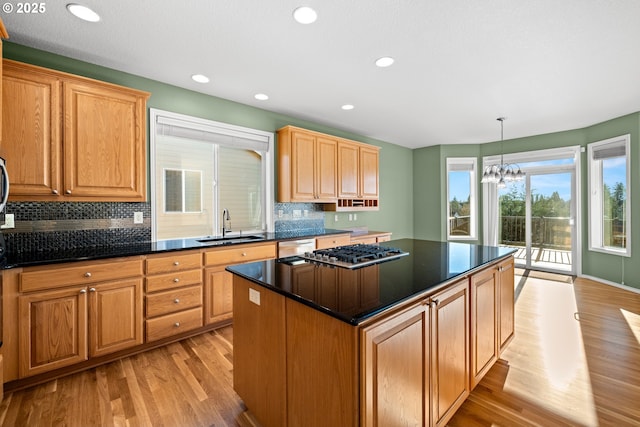 kitchen featuring sink, stainless steel appliances, an inviting chandelier, light hardwood / wood-style flooring, and a kitchen island