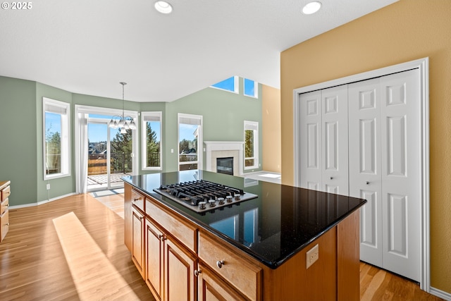 kitchen with a chandelier, a center island, stainless steel gas cooktop, pendant lighting, and light hardwood / wood-style flooring