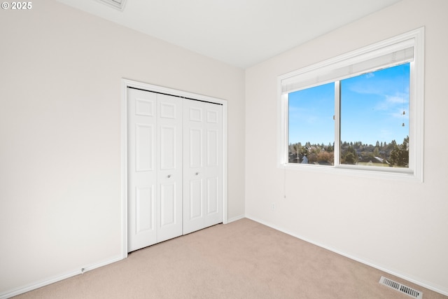 unfurnished bedroom featuring a closet and light carpet