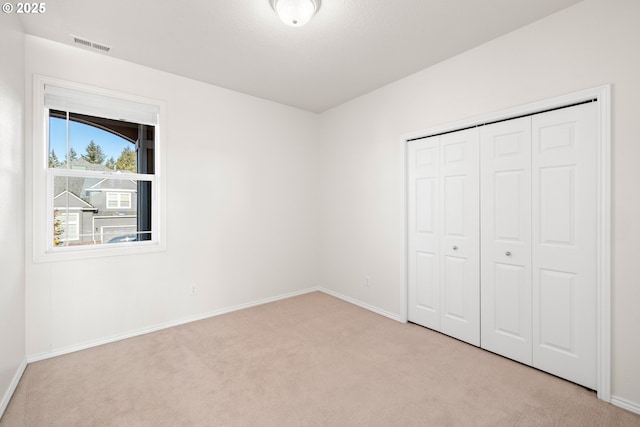 unfurnished bedroom featuring light colored carpet and a closet