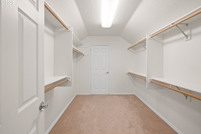 walk in closet featuring light carpet and lofted ceiling