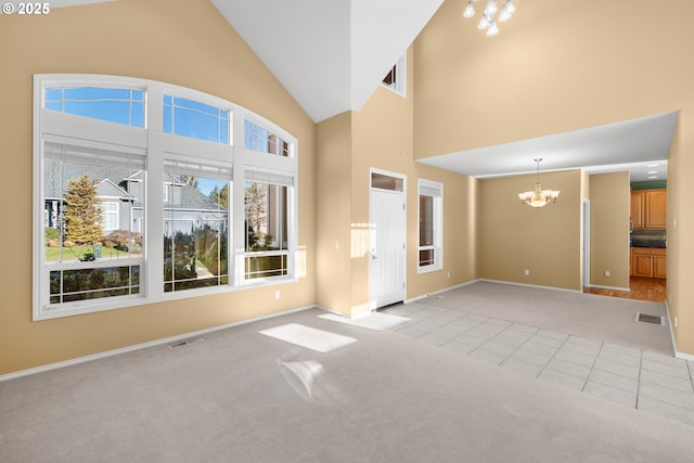 unfurnished living room featuring a towering ceiling, a notable chandelier, and light colored carpet