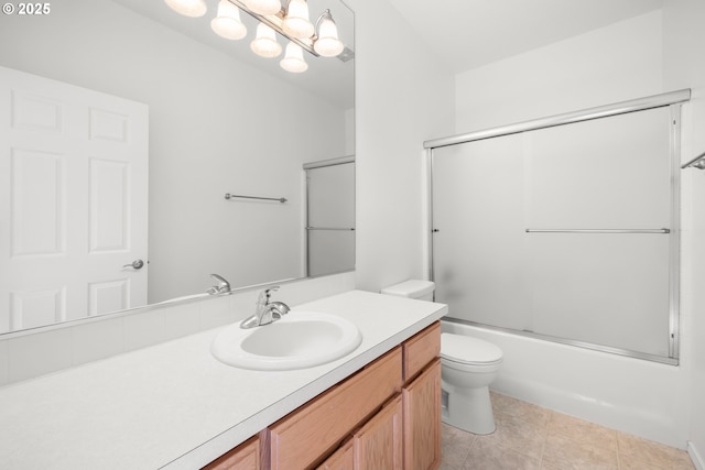 full bathroom featuring combined bath / shower with glass door, tile patterned floors, vanity, and toilet