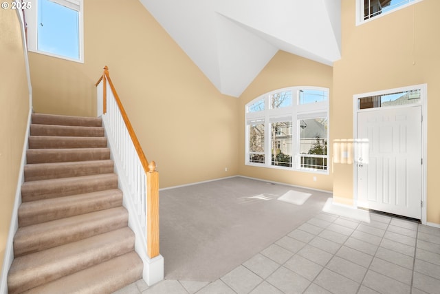 foyer entrance featuring high vaulted ceiling and light colored carpet