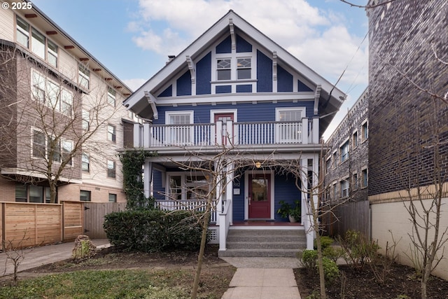 view of front of property featuring covered porch, fence, and a balcony