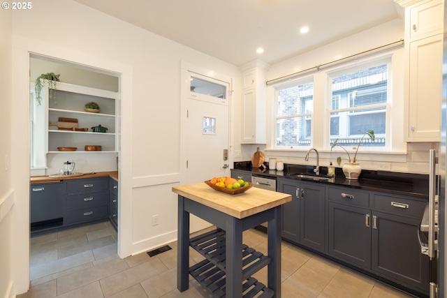 kitchen featuring butcher block countertops, visible vents, a sink, and light tile patterned flooring