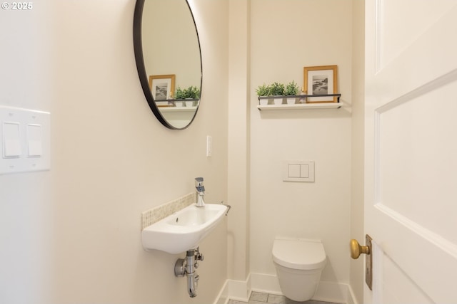 bathroom featuring a sink, toilet, and baseboards