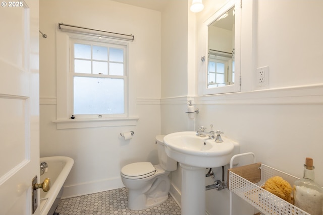 full bath with toilet, a freestanding tub, baseboards, and tile patterned floors