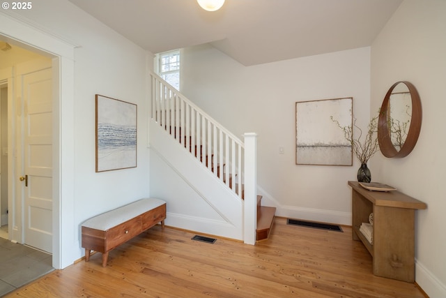 staircase with visible vents, baseboards, and wood finished floors