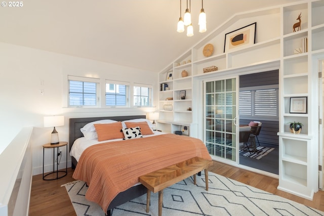 bedroom with lofted ceiling, baseboards, wood finished floors, and an inviting chandelier