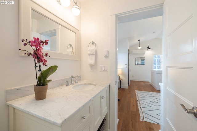 bathroom featuring baseboards, lofted ceiling, wood finished floors, a wall mounted air conditioner, and vanity