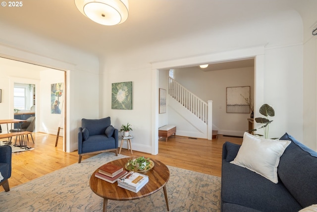 living area featuring stairs, baseboards, and wood finished floors