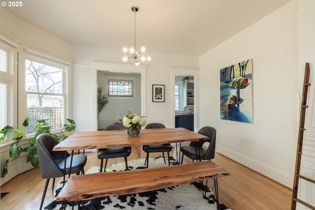 dining space with a chandelier, baseboards, visible vents, and light wood-style floors