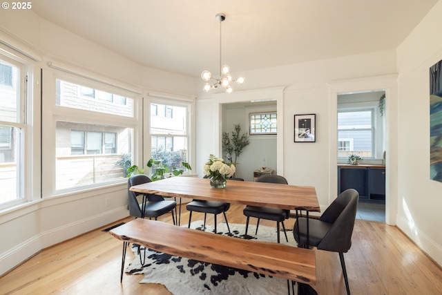 dining space with light wood-style flooring, baseboards, and a notable chandelier