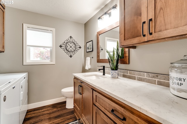 bathroom with hardwood / wood-style flooring, independent washer and dryer, vanity, and toilet