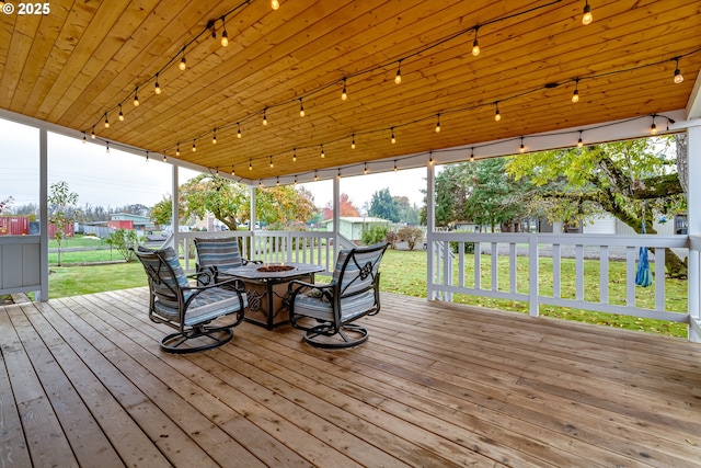 wooden terrace featuring a yard and a fire pit