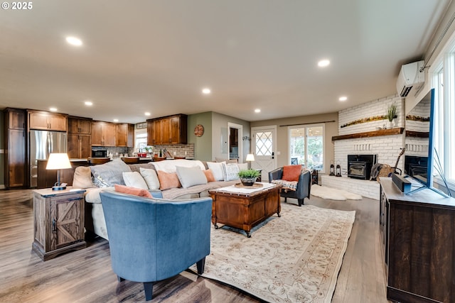 living room with a wall mounted air conditioner and light hardwood / wood-style flooring