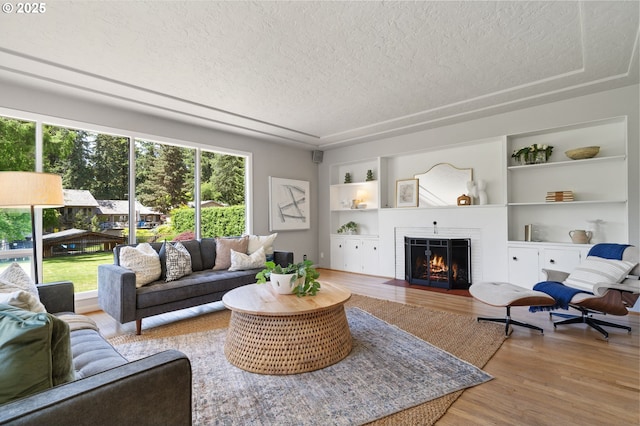 17787 Kelok Rd, Lake Oswego, OR 97034 - living room featuring a textured ceiling, wood finished floors, a fireplace with flush hearth, and built in shelves